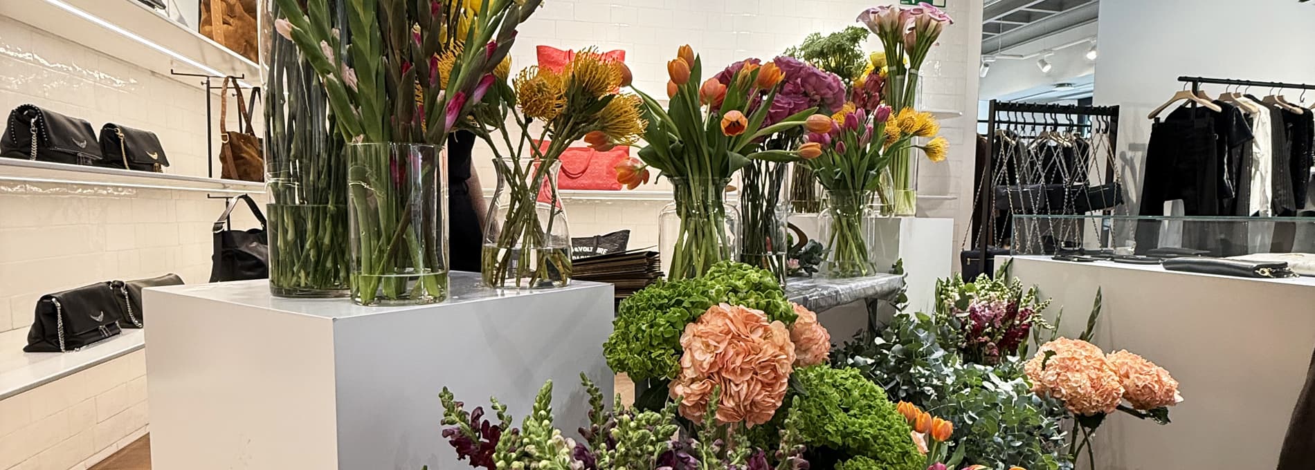barra floral premium con flores frescas de temporada, recipientes elegantes y presentación editorial, en un evento cuidado y luminoso.