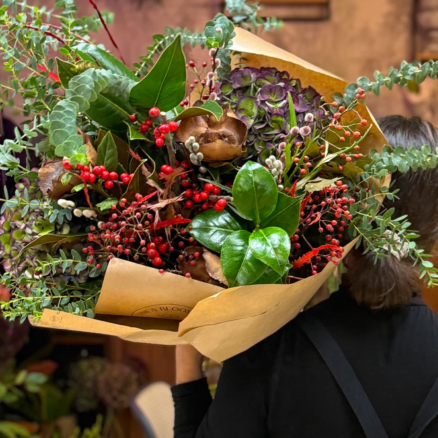 Florista sosteniendo el ramo navideño de temporada de Lumea Blooms en tamaño grande